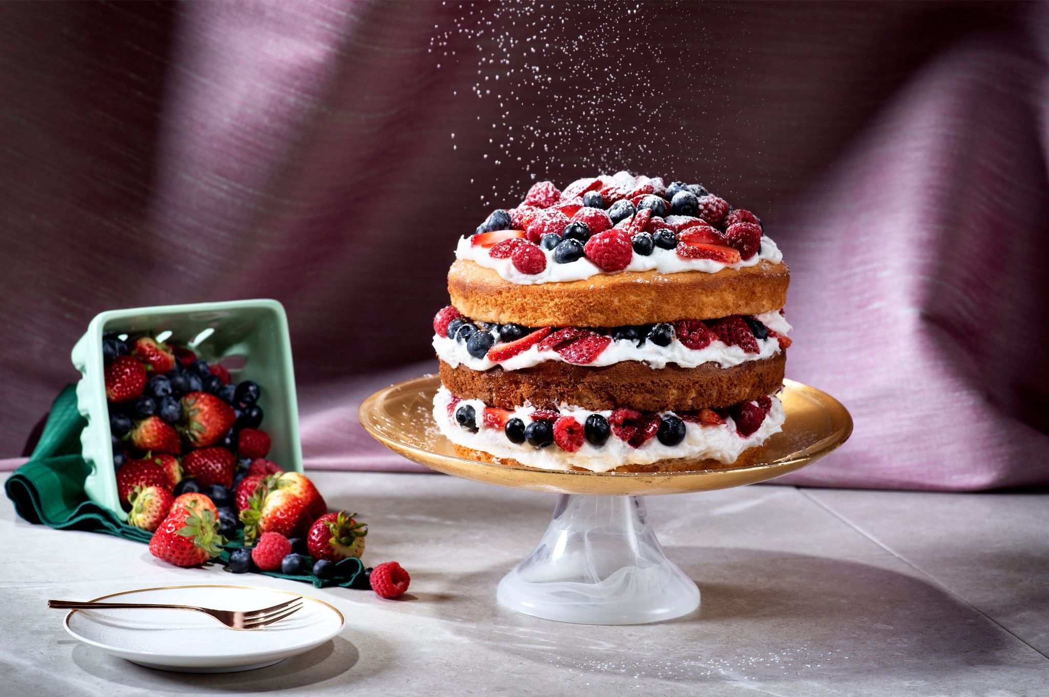 Caitlin Boyle photography of a dessert which includes a three layer cake topped with fresh berries.